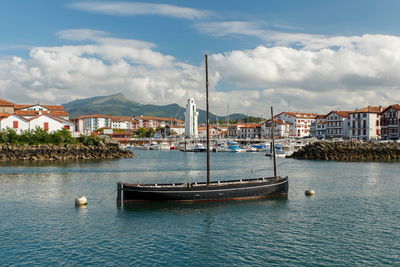 Sailboats moored on harbor by sea against sky