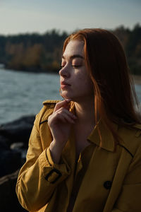 Beautiful woman in coat sitting at beach