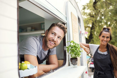 Happy male and female food truck owners looking away