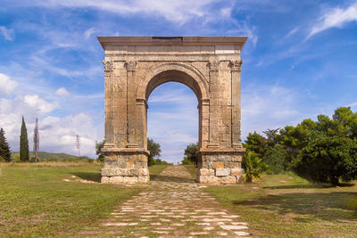 View of arch on field against cloudy sky