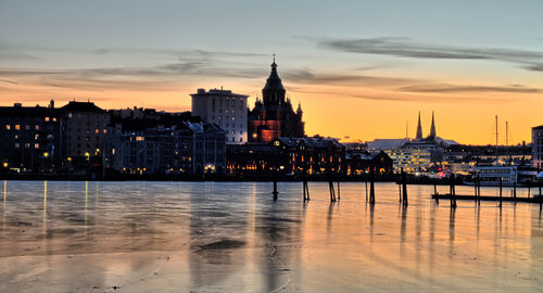 Illuminated buildings in city at sunset