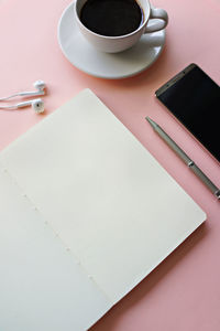 Directly above shot of personal accessory with mobile phone by coffee over pink background