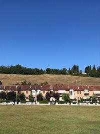 Houses on field against clear blue sky