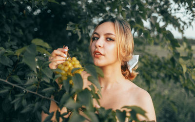 Portrait of young woman standing against plants