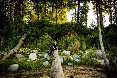 Man standing on tree trunk in forest