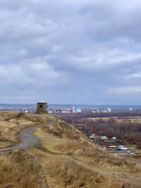 Scenic view of land by buildings against sky