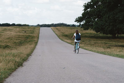 Rear view of woman riding bicycle on road