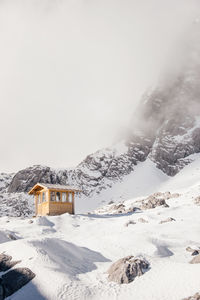 House on snow covered mountain against sky