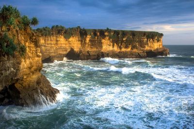 Rock formations on sea shore against sky