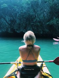 Rear view of woman kayaking in sea against mountain