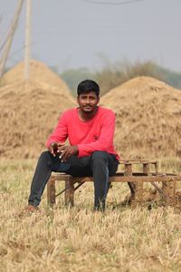 Portrait of young man sitting on field