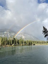 Scenic view of rainbow over lake against sky