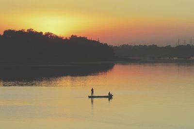 Silhouette boat in lake against sky during sunset