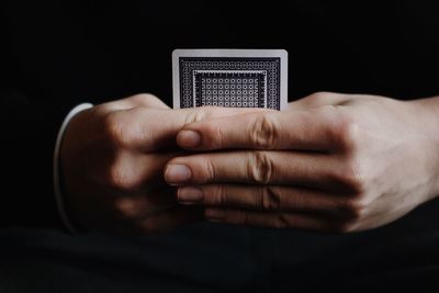 Close-up of man holding hand over black background