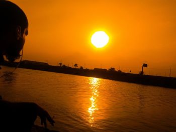 Silhouette man by sea against sky during sunset