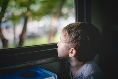 Close-up of boy looking through window of car