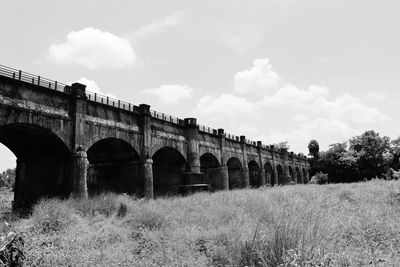 Arch bridge on field against sky