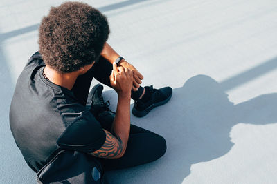 High angle view of man sitting on footpath