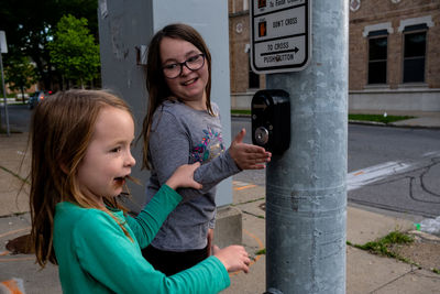 Sisters playing with crosswalk button at stop light