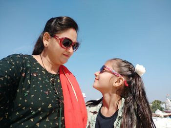 Smiling other and daughter standing against sky