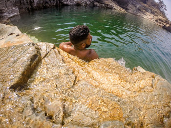 High angle view of young man wearing sunglasses swimming in sea