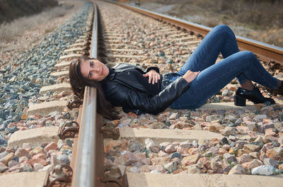 Low section of woman sitting on railroad track