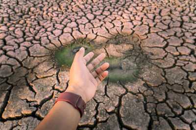 High angle view of human hand on cracked land