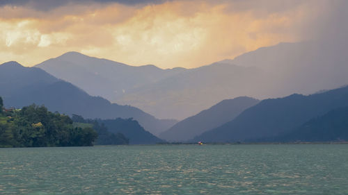 Scenic view of lake by mountains against sky during sunset