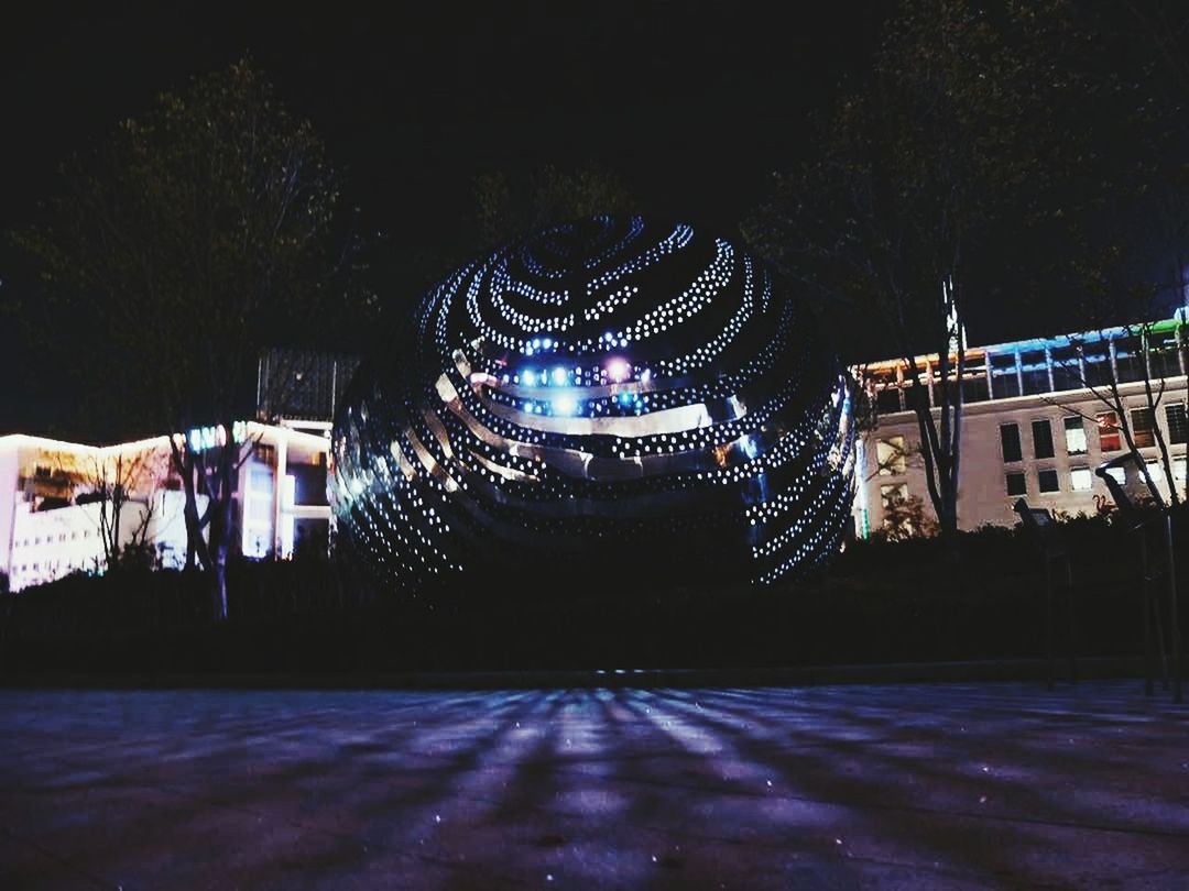 ILLUMINATED BUILT STRUCTURE WITH TREES IN BACKGROUND