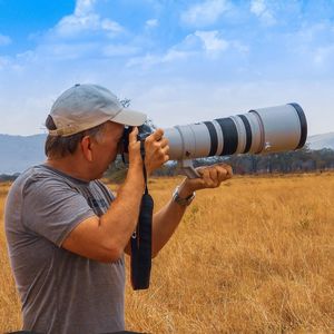 Side view of man photographing camera on field