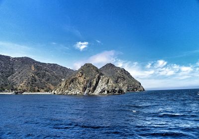 Scenic view of sea and mountains against blue sky