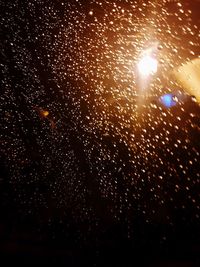 Full frame shot of raindrops on illuminated street at night