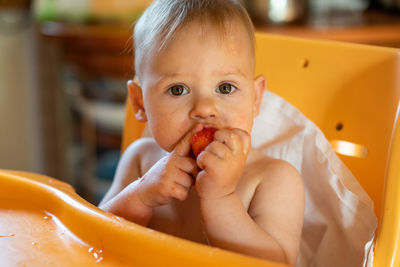 Portrait of cute baby girl eating fruit