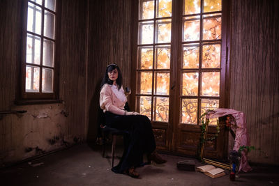 Portrait of young woman sitting on chair at home