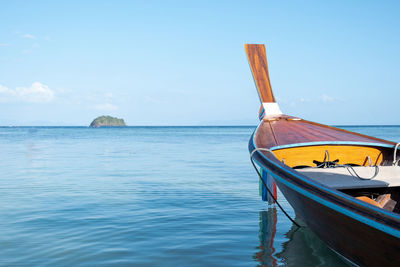 Boat moored on sea against blue sky