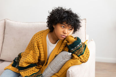 Portrait of young woman sitting on sofa at home