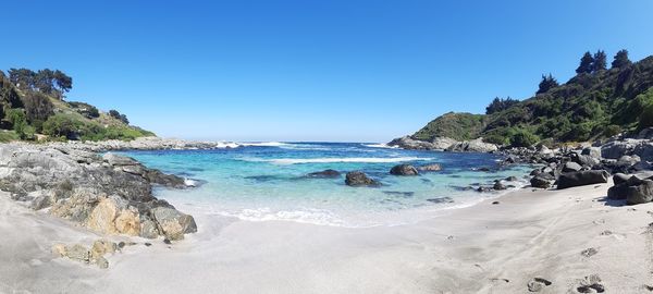 Scenic view of beach against clear blue sky