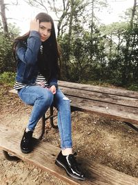 Full length portrait of young woman sitting outdoors