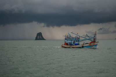 Boat in sea against storm clouds