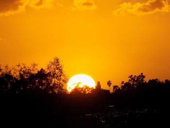 Silhouette trees against orange sky