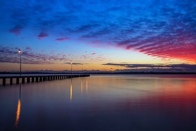 Pier over sea against sky during sunset