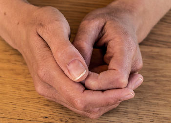 Close-up of person with hands clasped on table