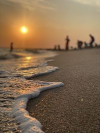 Surface level of beach against sky during sunset