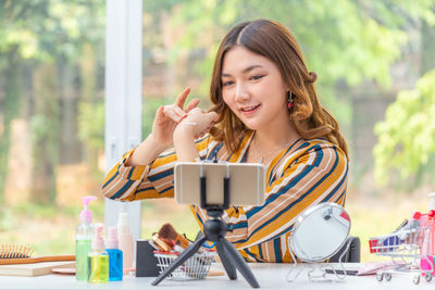 Portrait of young woman using phone while sitting on table