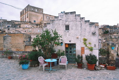 Empty chairs and tables against buildings in city