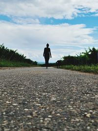 Rear view of woman standing on road against sky