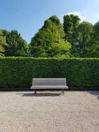 Empty bench in park against sky