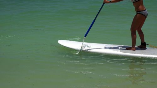 Low section of woman standing on paddleboard