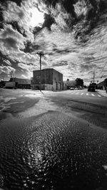 Empty road by buildings in city against sky