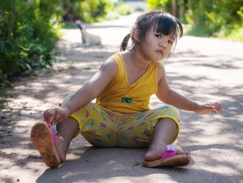 Cute girl looking away while sitting outdoors